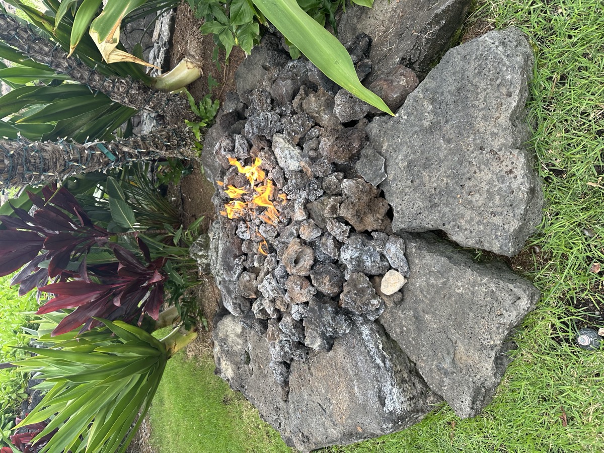 KAZ fire pit with lava rock surround in tropical garden